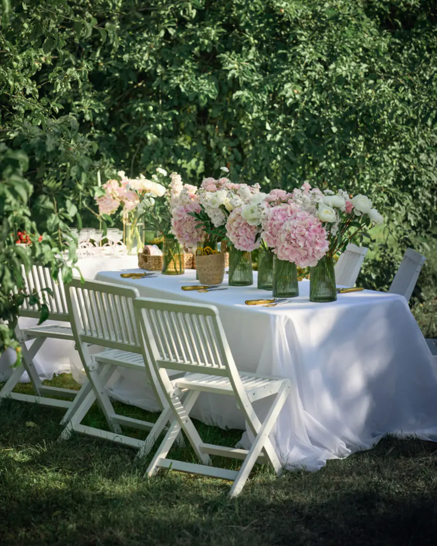 Outdoor table with pink hydrangeas and white folding chairs