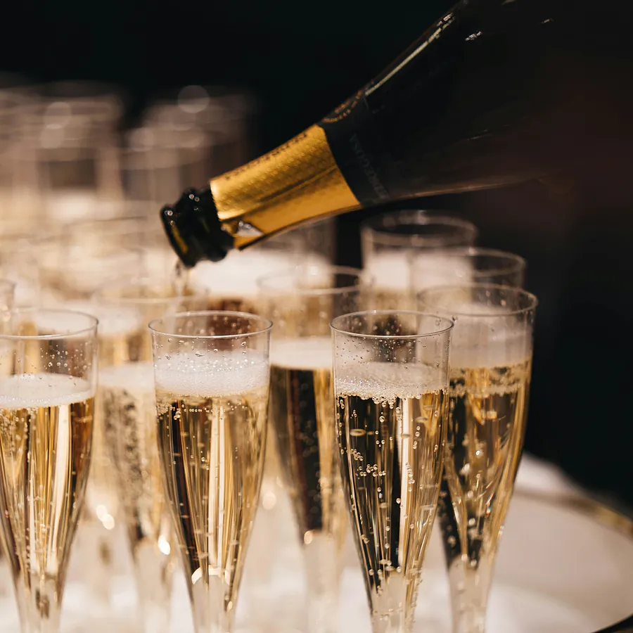 Champagne being poured into rows of flutes