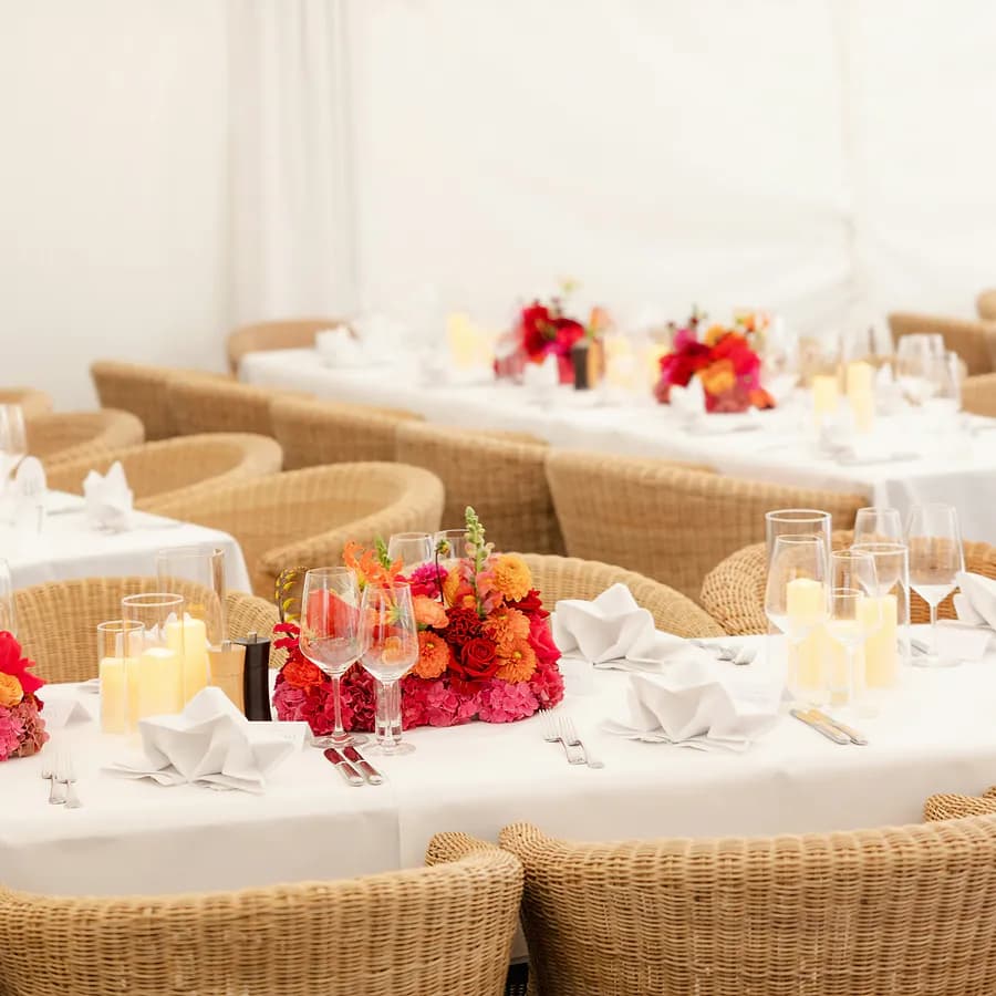 Long white dinner tables with red floral centrepieces