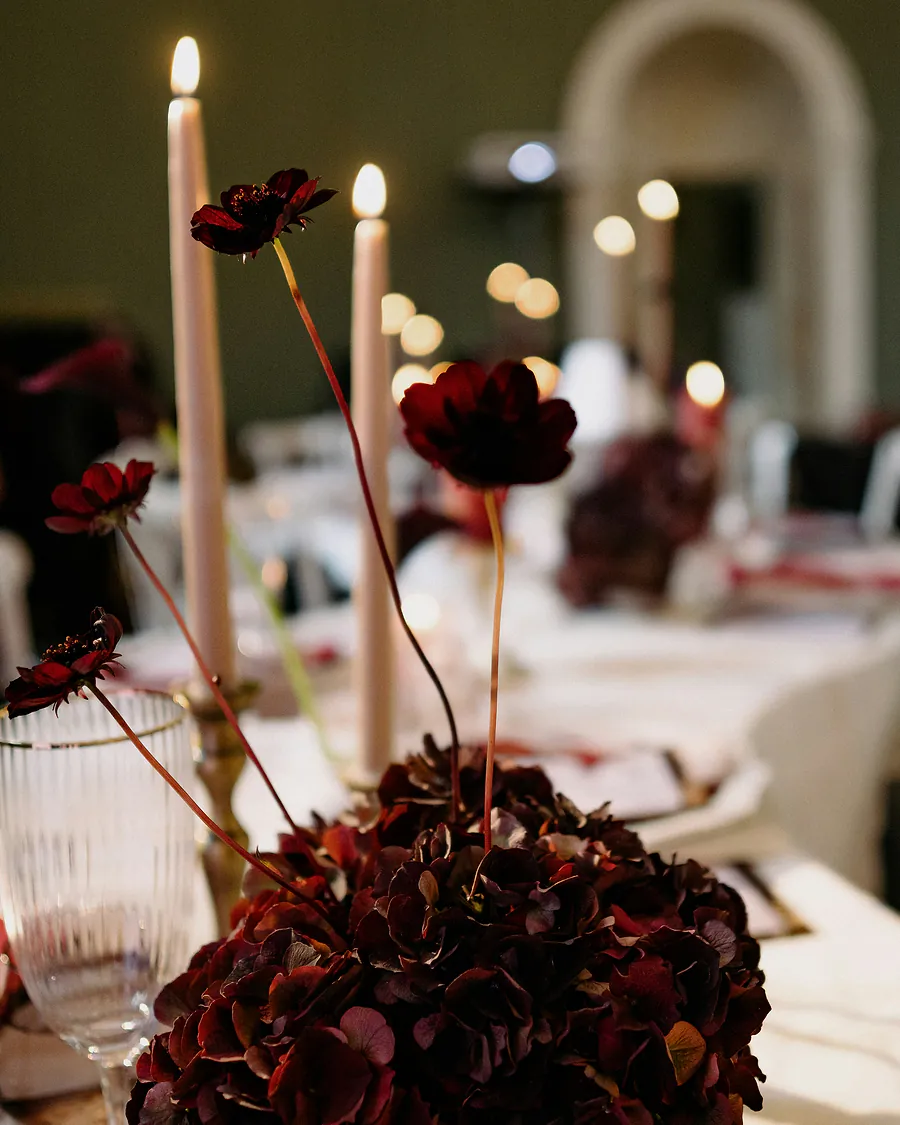 Dark red flowers and tall candles on a dinner table