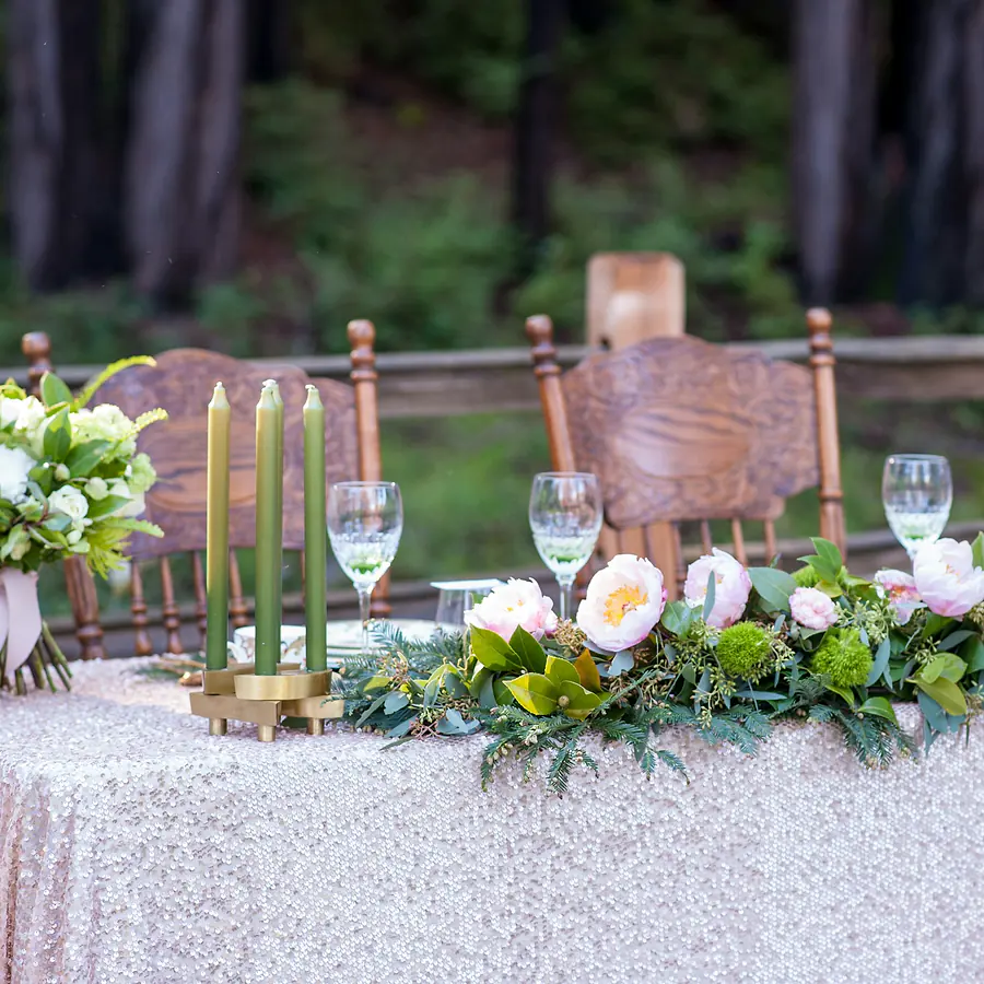 Sweetheart table with florals and green taper candles outdoors
